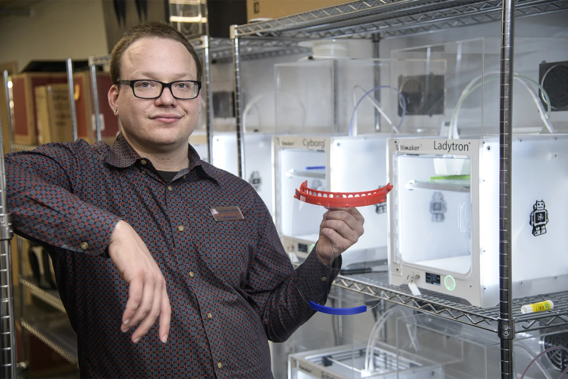 Tory Middlebrooks, of University Libraries, holds a face shield, which is designed to be worn in conjunction with addition PPE such as a mask. Middlebrooks runs the 3D printers that produced the headbands for the face shields created by University of Arizona employees and students inside makerspaces across campus. The effort was well underway in early April.