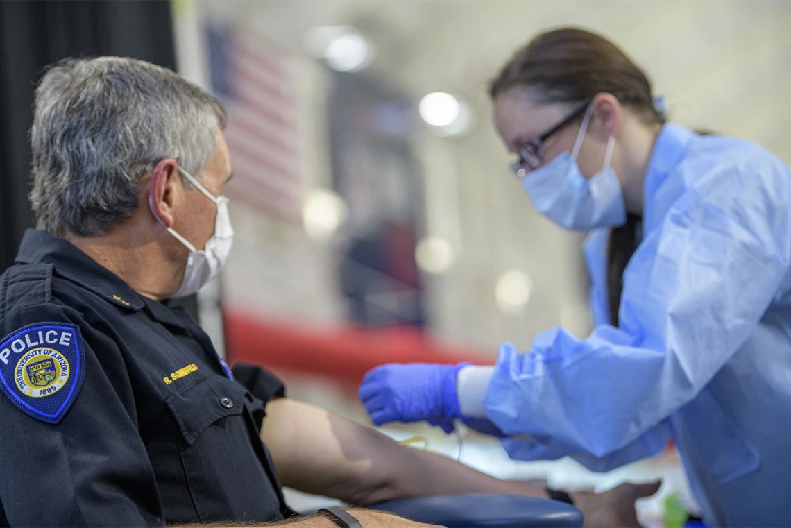 A health care worker prepares to apply a bandage to a police officer who has been tested.