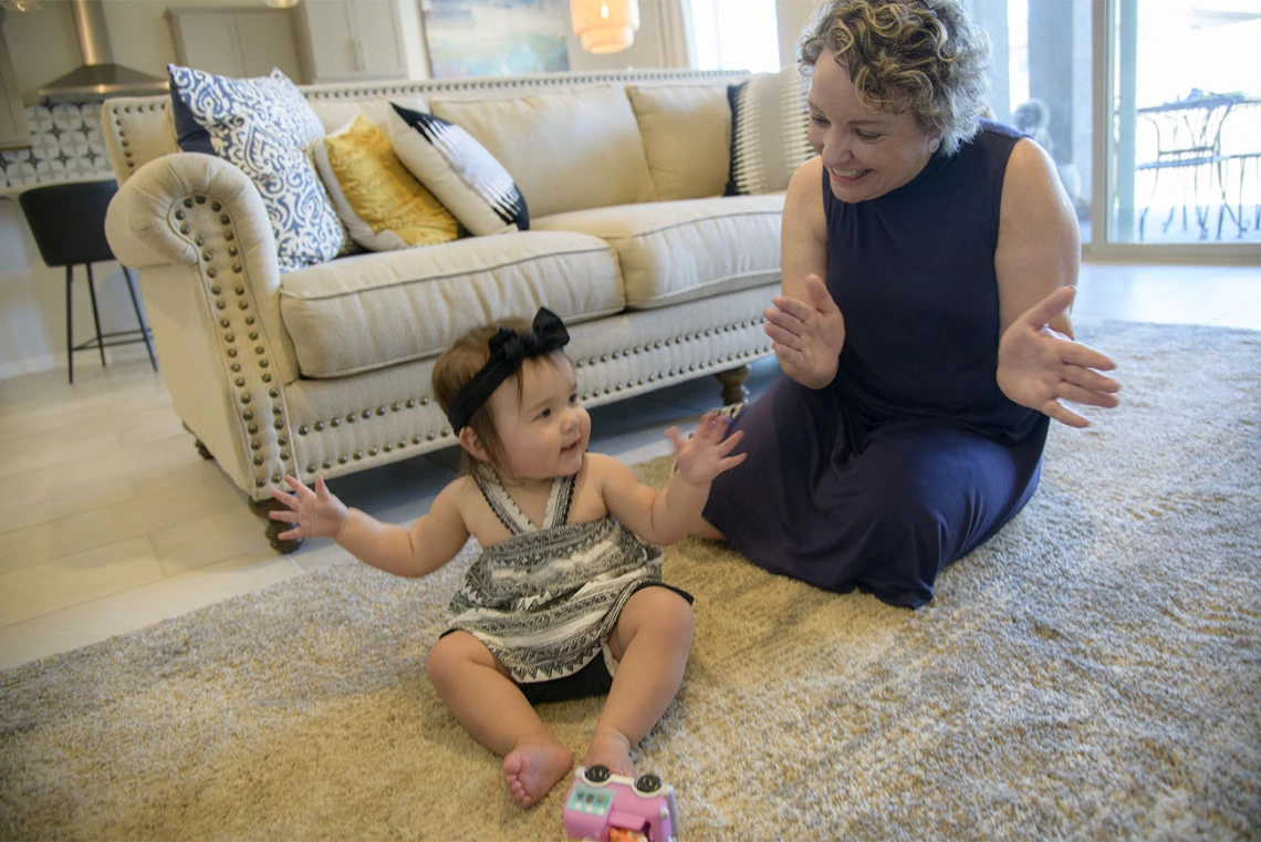 Woman clapping hands and playing with child at home