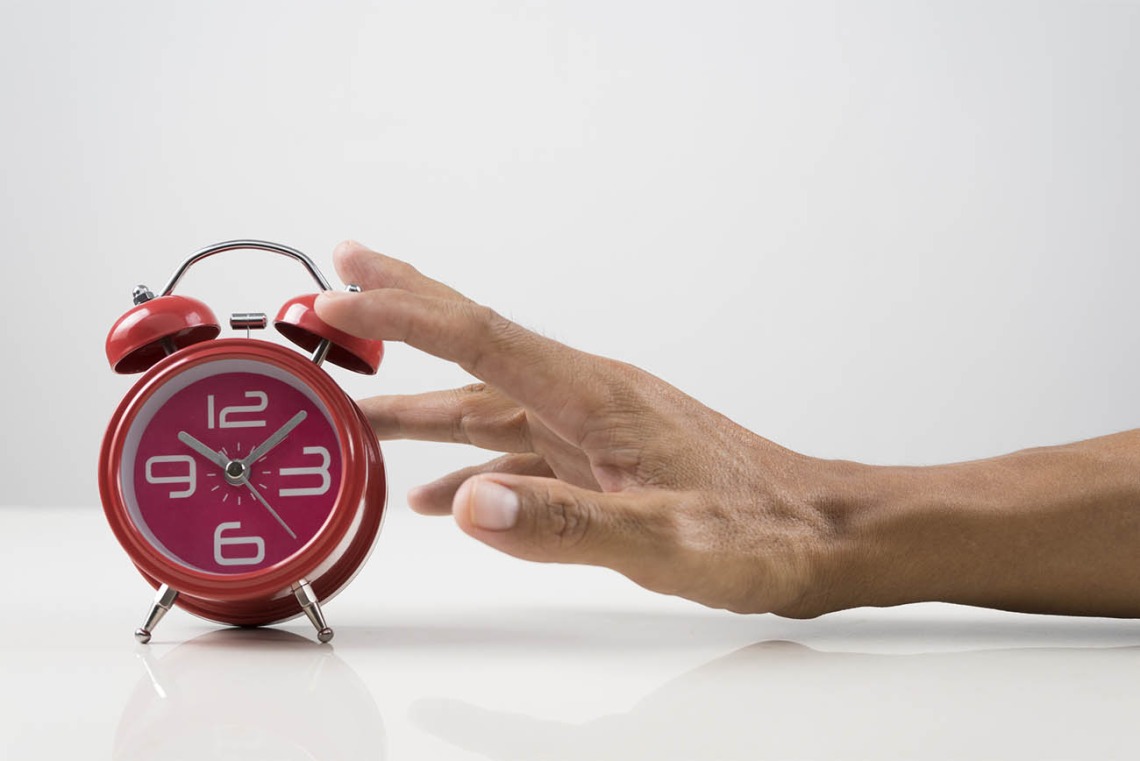 Hand reaching for red alarm clock