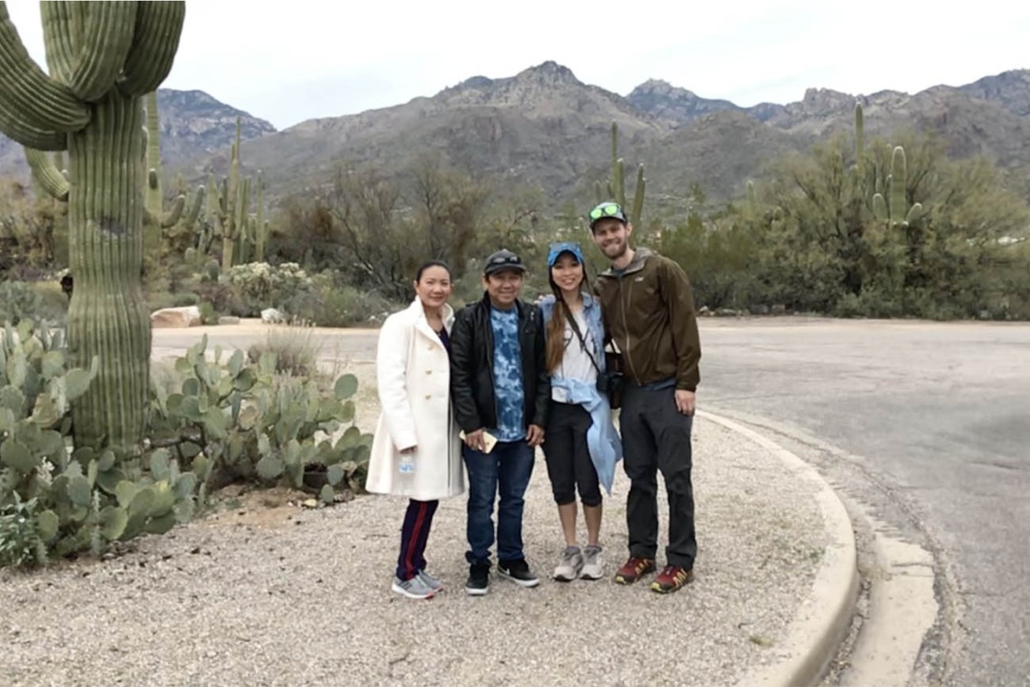 A family poses outside with mountains in the background and a saguaro