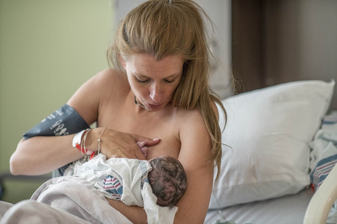Mother in hospital working to get her baby to latch on to breastfeed