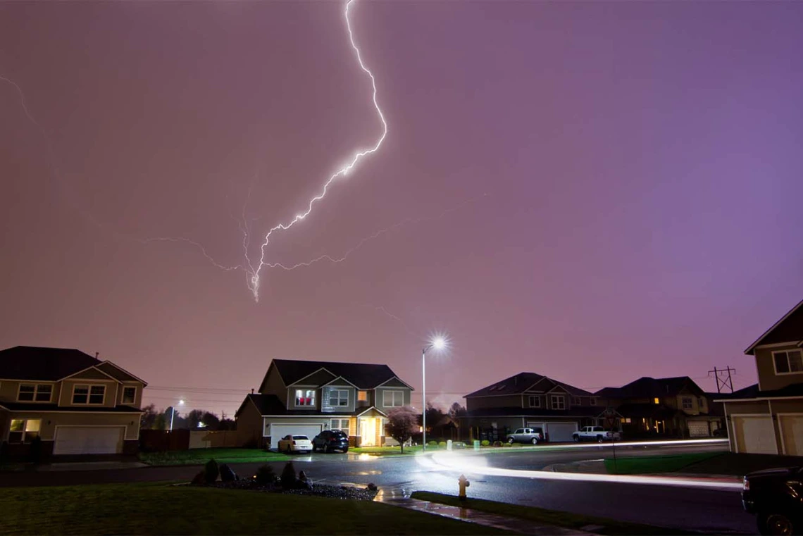 Lightning striking behind a neighborhood