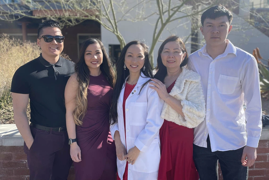 A family poses with a woman wearing a white coat in the middle