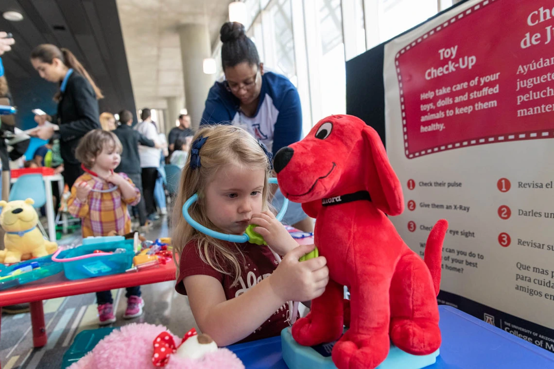 Little girl gives stuffed animal a check-up at the Wildcat Play Hospital sponsored by the University of Arizona College of Nursing.