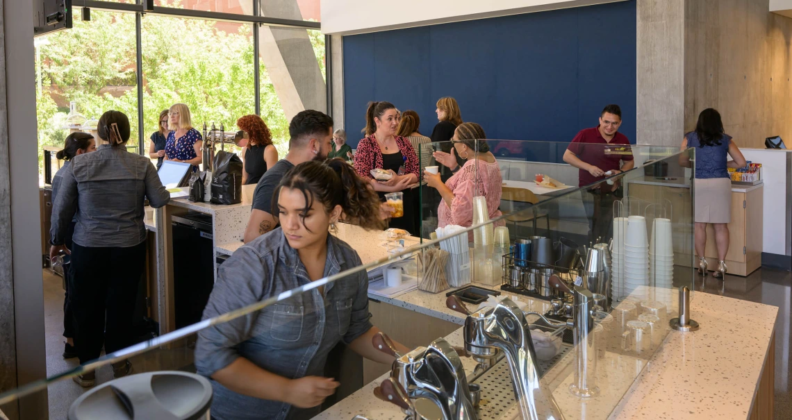 Crowd of people in a cafe with a coffee bar in the foreground. 