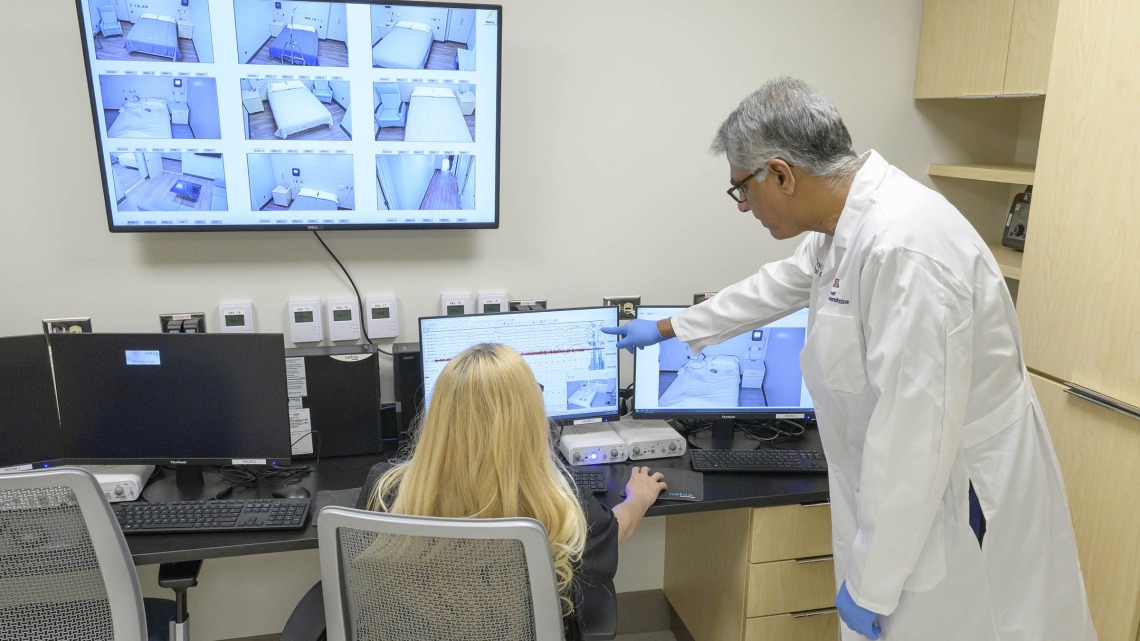 Sairam Parthasarathy, MD, director of the University of Arizona Health Sciences Center for Sleep, Circadian and Neuroscience Research, reviews test data in the control room of the center’s new facility with lead sleep technologist Sicily La Rue. 