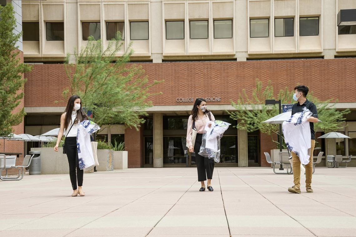 White coats in hand, three new members of the Class of 2024 leave the College of Medicine – Tucson building. From left: Lupita Molina, Julia Alvarenga Couto and Lawrence Sun.