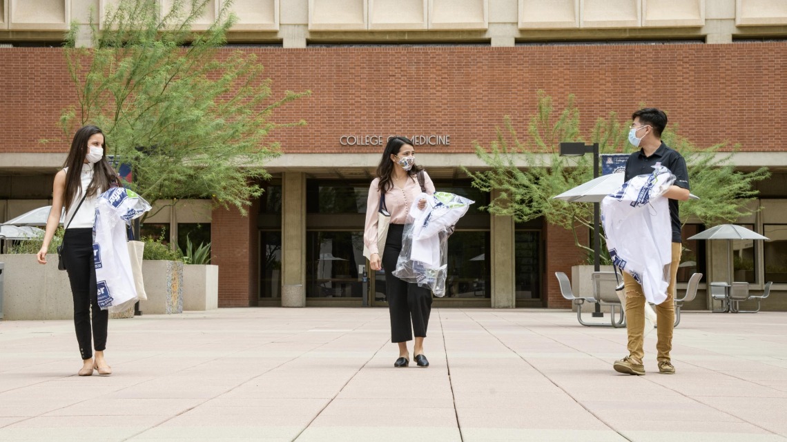 Students in the College of Medicine – Tucson Class of 2024 wear masks and keep a safe distance from one another as they pick up their white coats, the traditional activity marking the beginning of their four-year medical school experience.