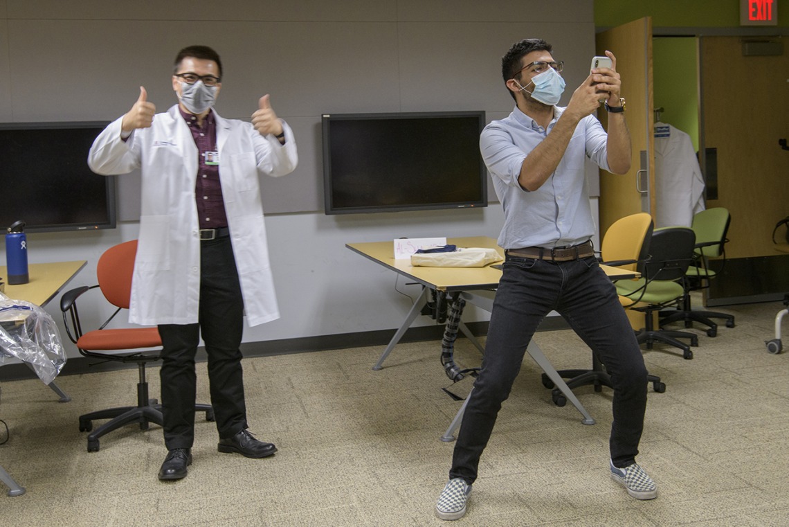 First-year medical student Daniel Nguyen of Santa Rita House tries on his white coat while first-year medical student Ahmed Al-Shamari takes a selfie with his new colleague.