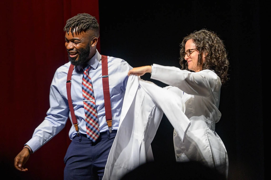 Atehkeng Zinkeng is presented his white coat by associate professor Audrey Baker, MD, during the UArizona College of Medicine – Tucson Class of 2026 white coat ceremony.