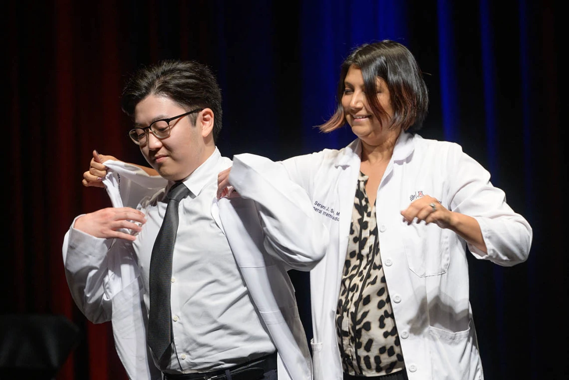 Andrew Endo is given his white coat by Serena Scott, MD, assistant professor of medicine, at the UArizona College of Medicine – Tucson Class of 2026 white coat ceremony.