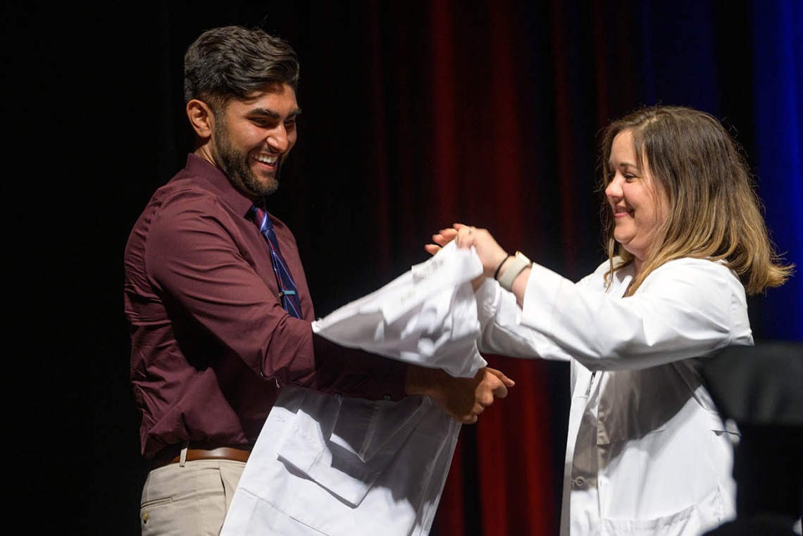Rorie Robinson prepares to be coated by clinical assistant professor Joy Bulger Beck, MD, at the UArizona College of Medicine – Tucson Class of 2026 white coat ceremony.