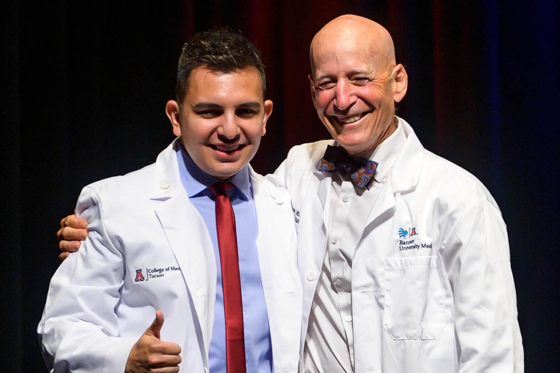 Adrian Franco pauses for a photo with professor Paul Gordon, MD, MPH, after receiving his white coat at the UArizona College of Medicine – Tucson Class of 2026 white coat ceremony.