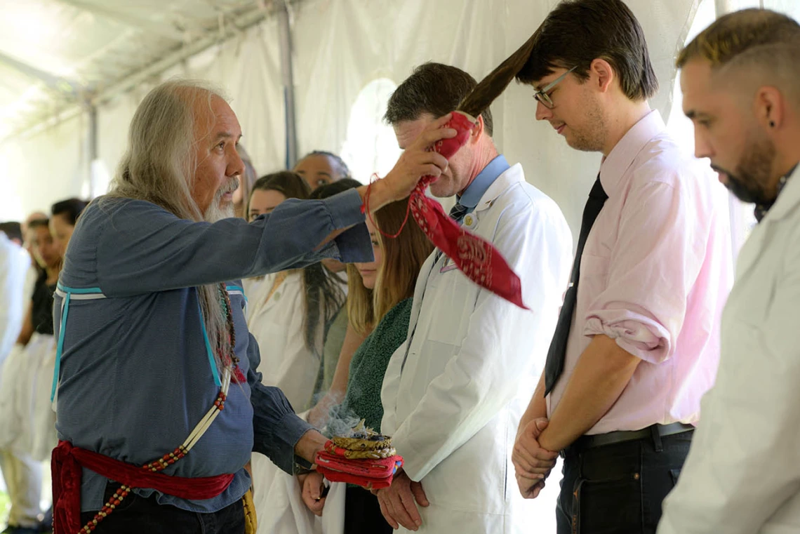 Carlos Gonzales, MD, blesses James V. Proffitt, PhD, an assistant professor of cellular and molecular medicine, with the smoke from sacred herbs and an eagle feather wand during the annual College of Medicine – Tucson Tree Blessing Ceremony.