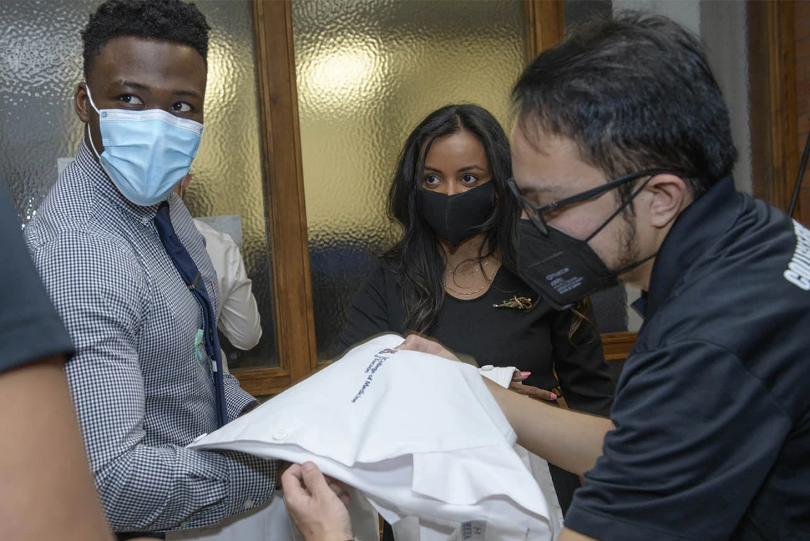 Class of 2024 students Oluwatobi Odeneye and Hannah Korah get their white coats neatly folded and draped over their arms prior to their white coat ceremony.
