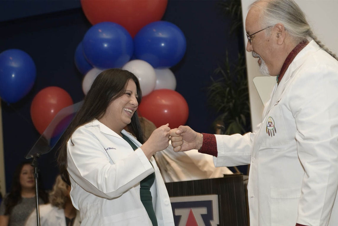 Erika Yee receives a fist bump from Carlos Gonzales, MD, FAAFP, assistant dean of curricular affairs at the UArizona College of Medicine – Tucson.