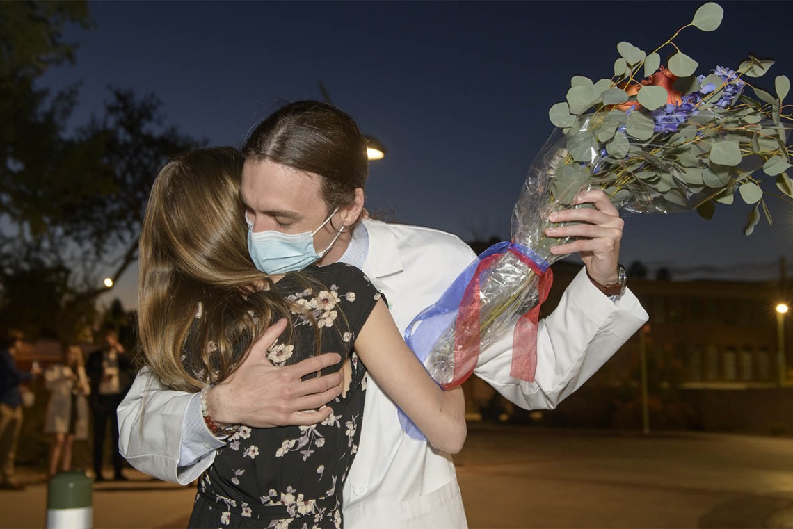 Benjamin Nichols receives flowers and a hug from his partner after his UArizona College of Medicine – Tucson class of 2024 white coat ceremony.