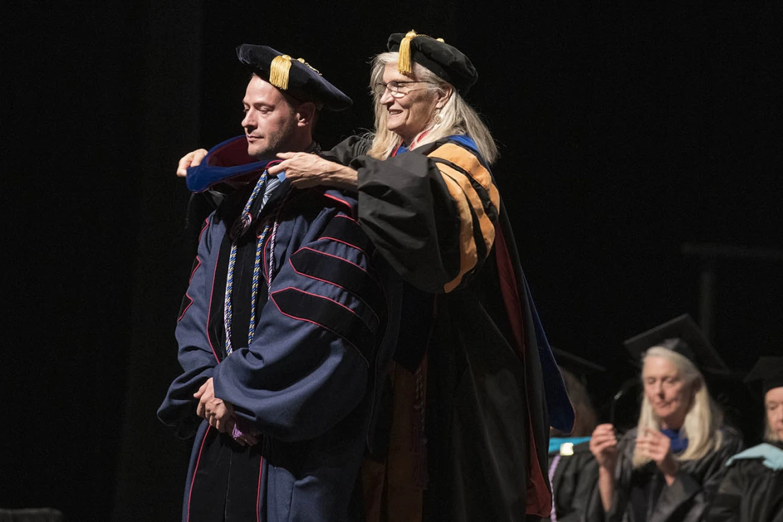 Monte Roberts, PhD, is hooded by Kimberly Shea, PhD, RN, CHPN, for earning his Doctor of Philosophy in Nursing during the UArizona College of Nursing 2022 spring convocation at Centennial Hall.