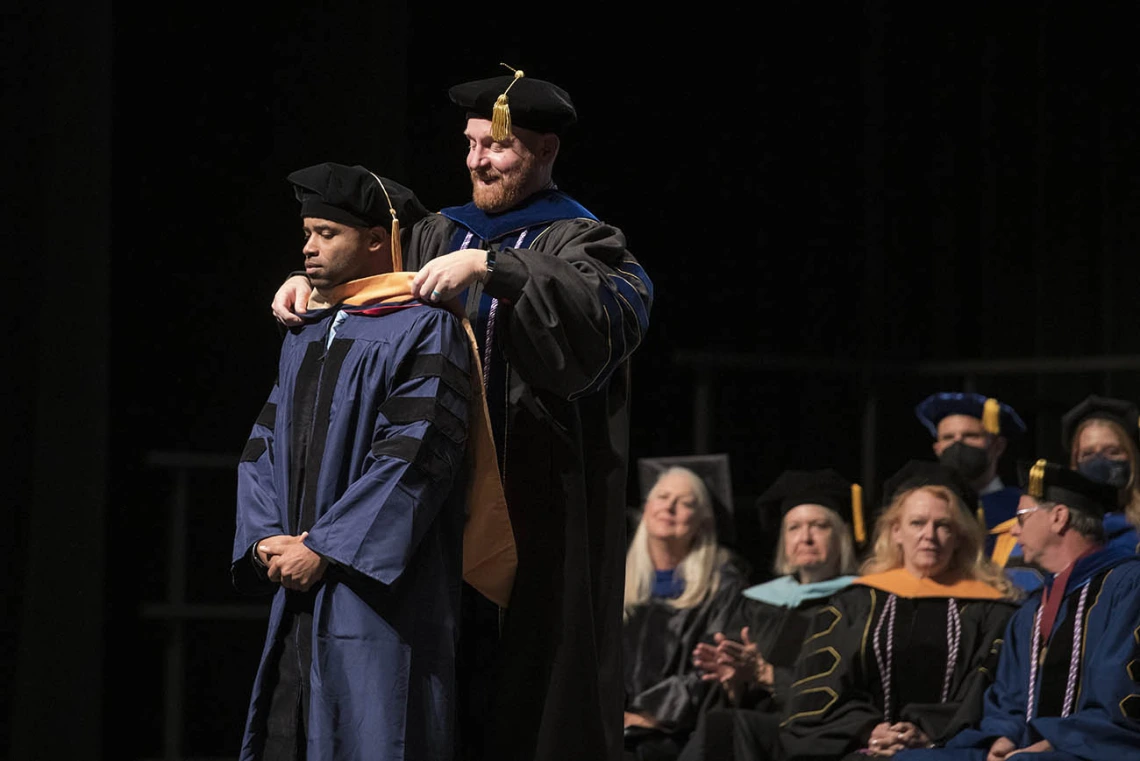 James Gibson, DNP, is hooded by Charles “Reggie” Elam, PhD, DNAP, CRNA, for earning his Doctor of Nursing Practice during the UArizona College of Nursing 2022 spring convocation at Centennial Hall. 