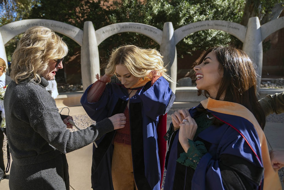Kristine Harmon (left) helps her daughter, Erika Harmon with her graduation gown as Sheema Zarezadeh buttons up her gown (right) before the College of Nursing fall convocation at Centenial Hall.