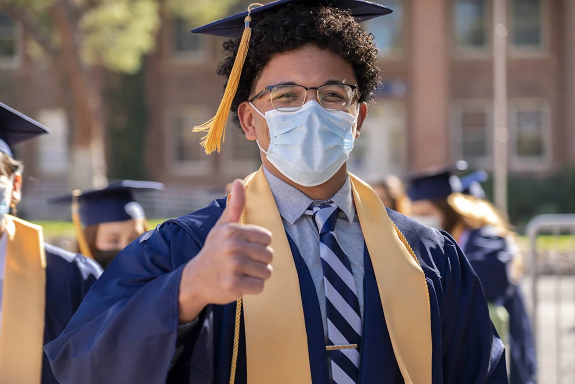 College of Nursing student Isaiah Buster signals that he is ready for the College of Nursing’s fall convocation as he walks into Centennial Hall.