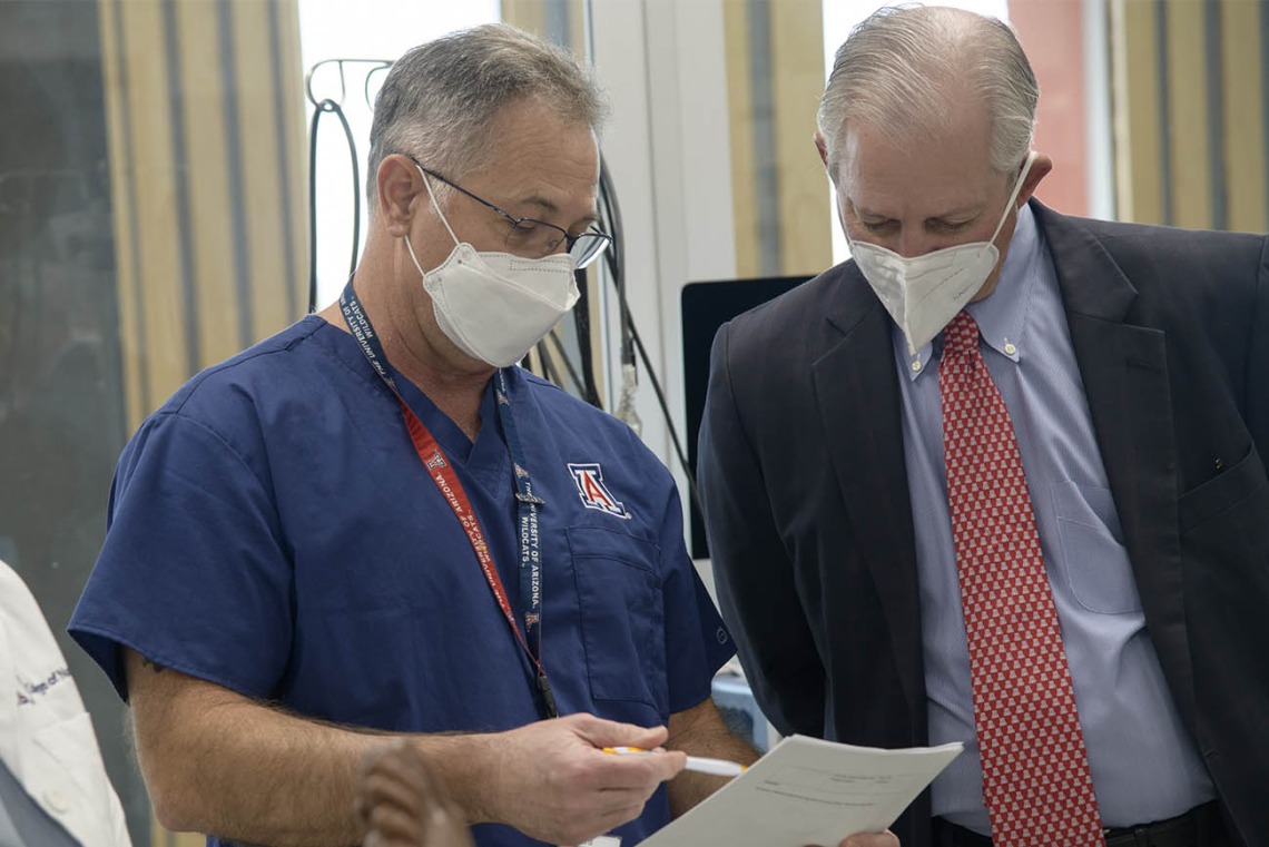 Jim Reed, DNP, CRNA, associate clinical professor, reviews the grading sheet he used while observing the CRNA students during a simulation with University of Arizona President Robert C. Robbins, MD. 