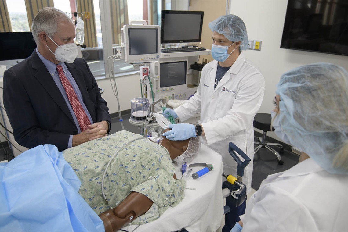 CRNA student Phillip Bullington, RN, (center), seeks input from University of Arizona President Robert C. Robbins, MD, during the simulation where the “patient’s” breathing was becoming very weak.  