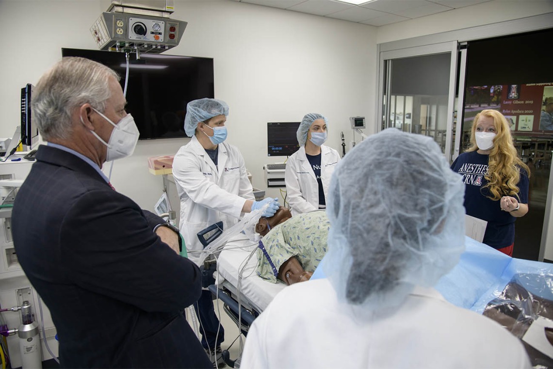 Kristie Hoch, DNP, CRNA, MS, RRT, (right) program administrator for the CRNA class, talks with her students and University of Arizona President Robert C. Robbins, MD, during a debriefing after the completion of their simulation. 