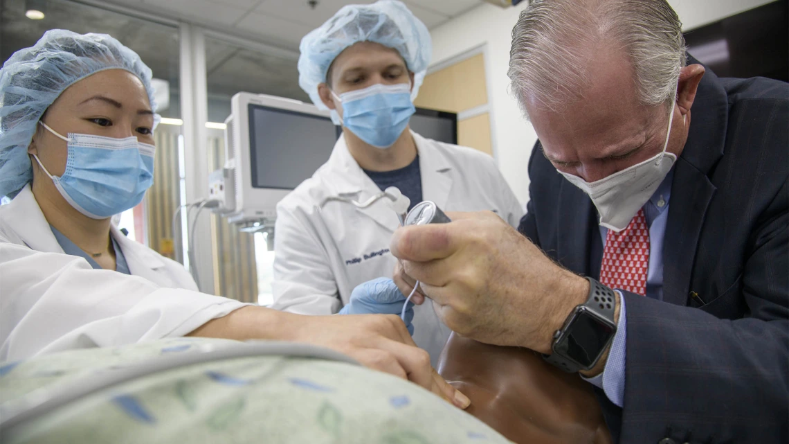 University of Arizona President Robert C. Robbins, MD, (right) recently visited the Arizona Simulation Technology and Education Center to observe second year Certified Registered Nurse Anesthetist (CRNA) students during their simulation. Instead of just observing, he was pressed into service as the surgeon during one simulation. CRNA students Alexa Deng, RN, (left) and Phillip Bullington, RN, assisted Dr. Robbins as he intubated a manikin. 