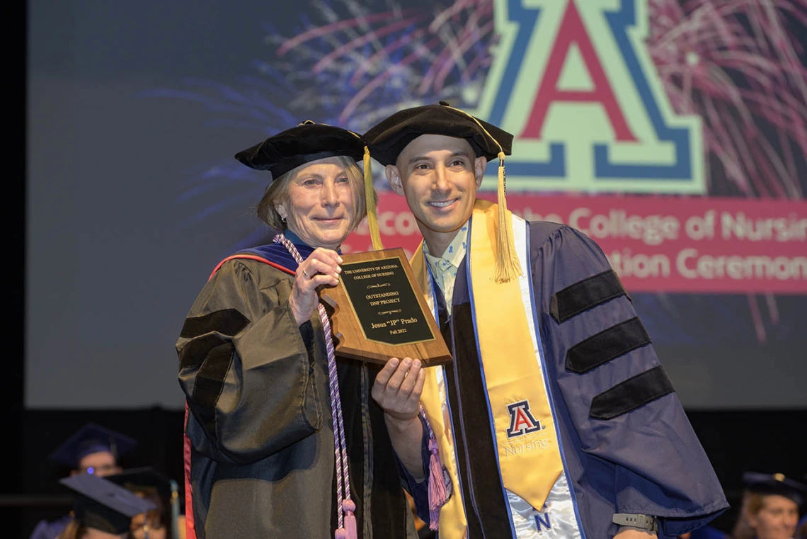 Jesus “JP” Prado, a Doctor of Nursing Practice graduate, is presented with the Outstanding DNP Project Award by Interim Dean Kathleen Insel, PhD, RN, during the UArizona College of Nursing fall convocation at Centennial Hall on Dec. 15. 