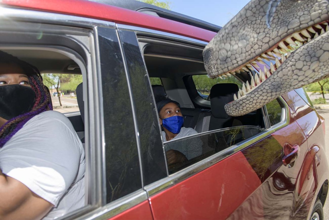 Doshia Davis, left, and Cy’Myah Murphy, keep a close eye on a nosey T-Rex as they begin the Connect2STEM drive-through event. 