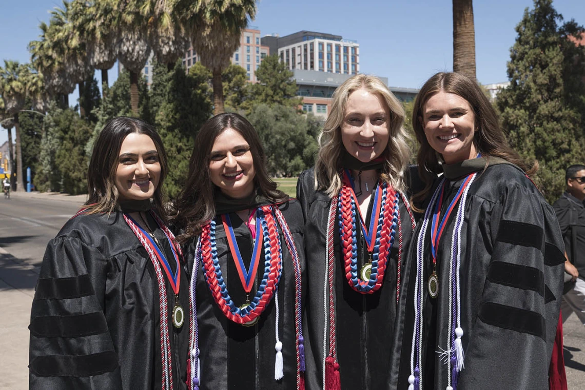 Hannah Muasher, PharmD, Sydni Martinez, PharmD, Lauren Kimsza, PharmD, and Sammantha Meyer, PharmD, pose for a photo outside Centennial Hall after the R. Ken Coit College of Pharmacy 2022 spring convocation at Centennial Hall.