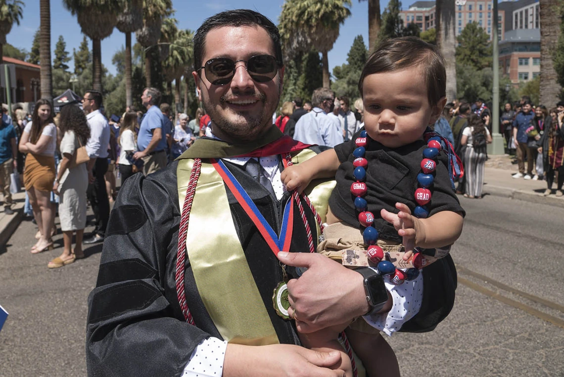 David Alvarado, PharmD, holds his son after the R. Ken Coit College of Pharmacy 2022 spring convocation at Centennial Hall.