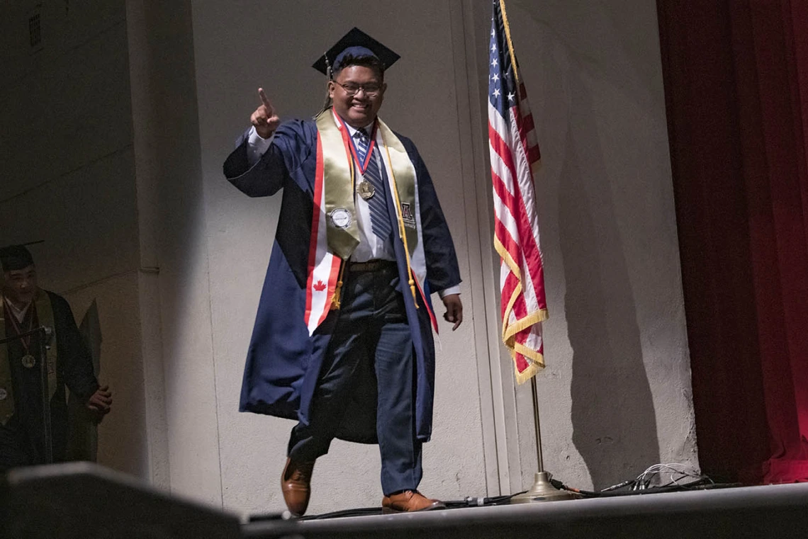 Bachelor of Science in Pharmaceutical Sciences graduate Kurt Carlos points to the audience as his name is called during the R. Ken Coit College of Pharmacy 2022 spring convocation at Centennial Hall. 