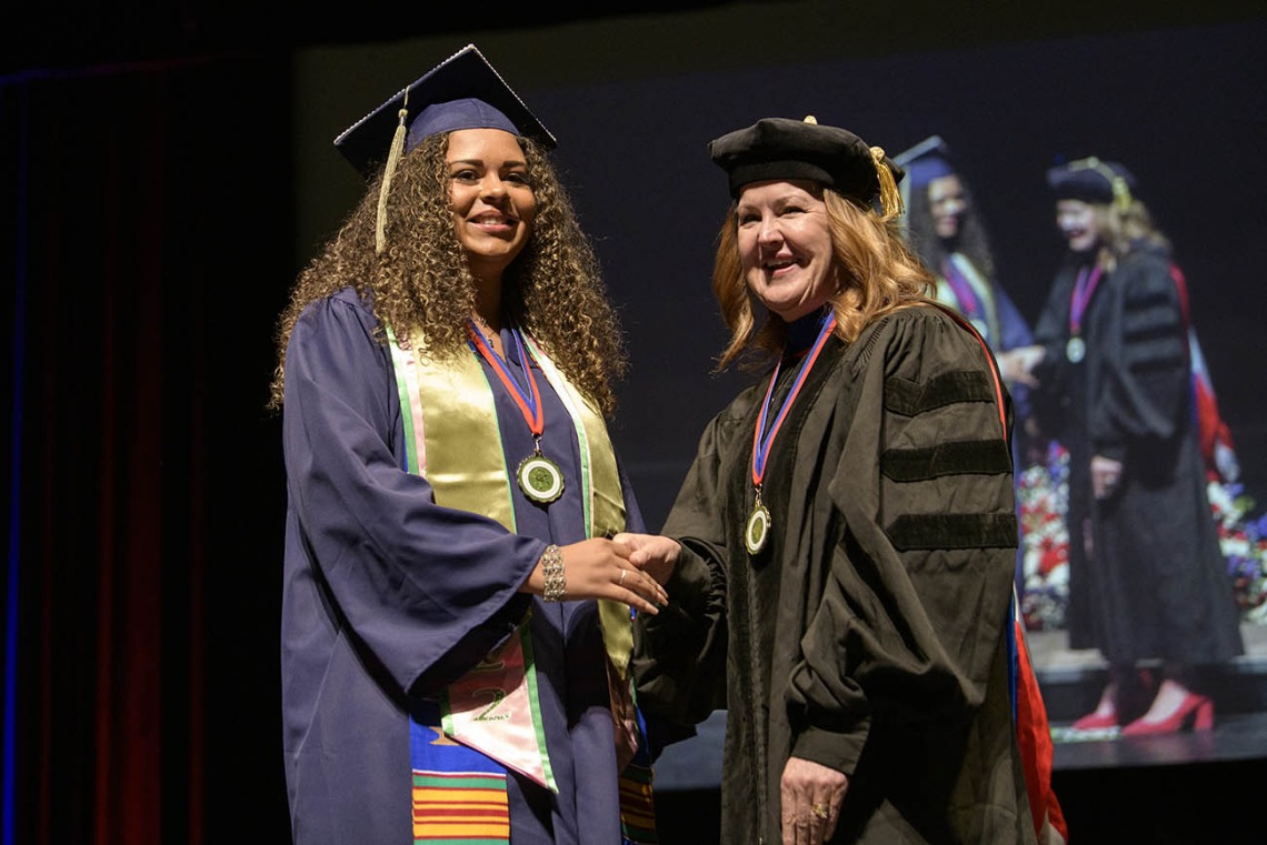 Jalynne Decker shakes hands with associate professor Jennifer Schnellmann, PhD, after receiving her Bachelor of Science in Pharmacological Sciences during the R. Ken Coit College of Pharmacy 2022 spring convocation at Centennial Hall.