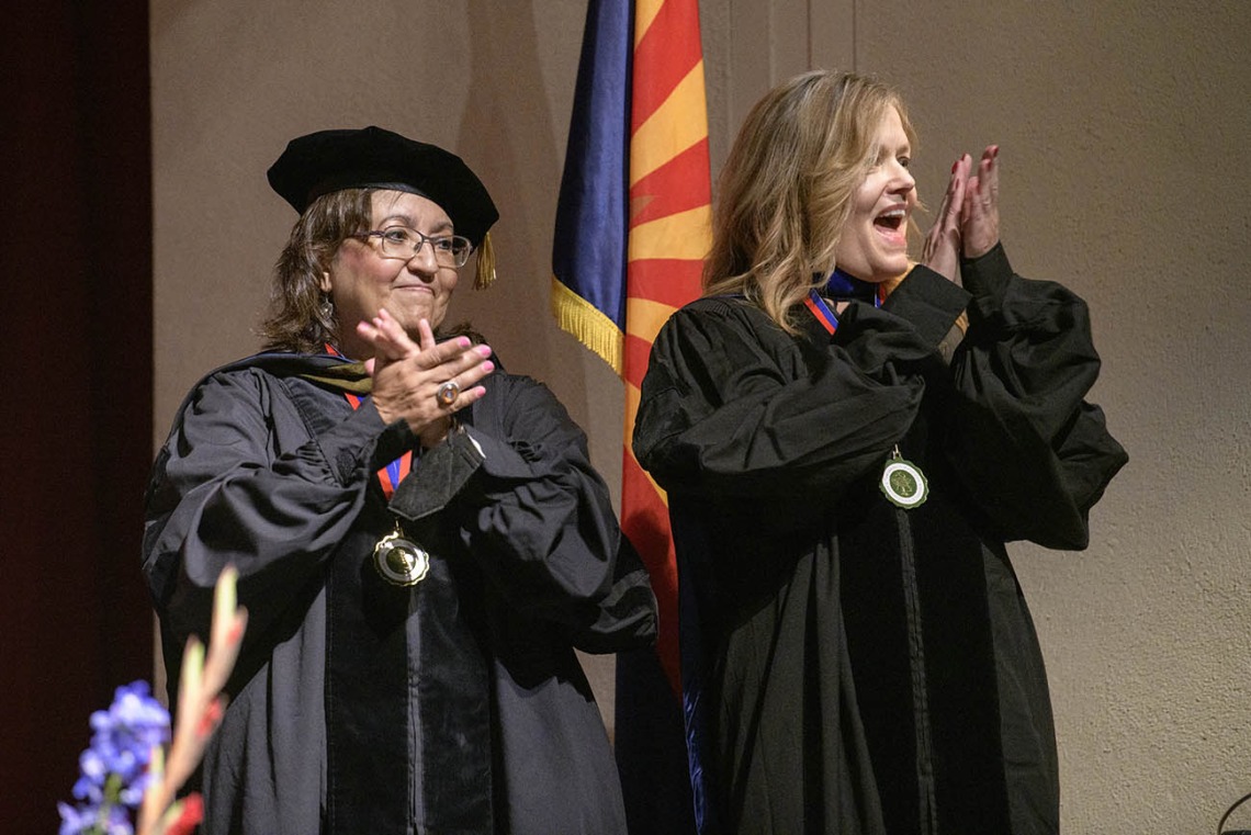 (From left) Nancy Alvarez, PharmD, BCPS, and Terri Warholak, PhD, RPh, applaud students as they walk across the stage during the R. Ken Coit College of Pharmacy 2022 spring convocation at Centennial Hall.