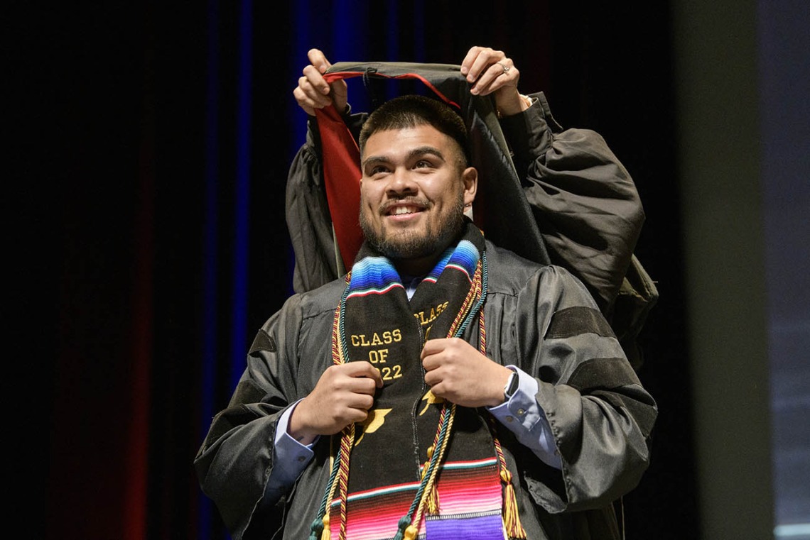 Jonathan Corrales, PharmD, is hooded by Ashley Campbell, PharmD, BCPS, for earning his Doctor of Pharmacy during the R. Ken Coit College of Pharmacy 2022 spring convocation at Centennial Hall.