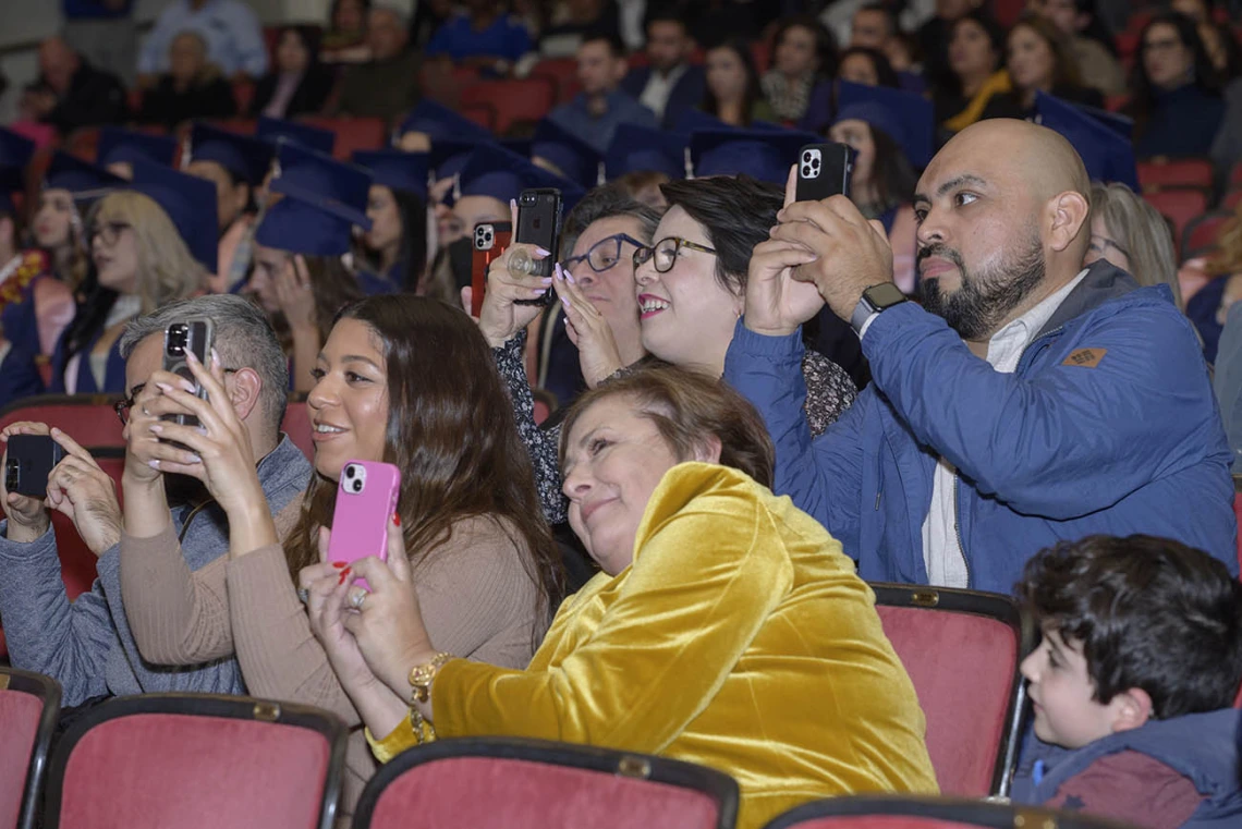 Italia Trejo’s family members wait to capture the moment she is hooded as a Master of Public Health graduate at the Mel and Enid Zuckerman College of Public Health fall convocation.