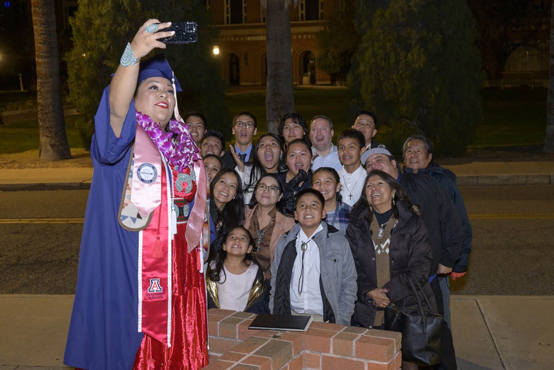 Bahozhoi Kinsel-Gishie takes a selfie with her family outside of Centennial Hall after receiving a Bachelor of Science in Public Health degree at the Mel and Enid Zuckerman College of Public Health fall convocation.