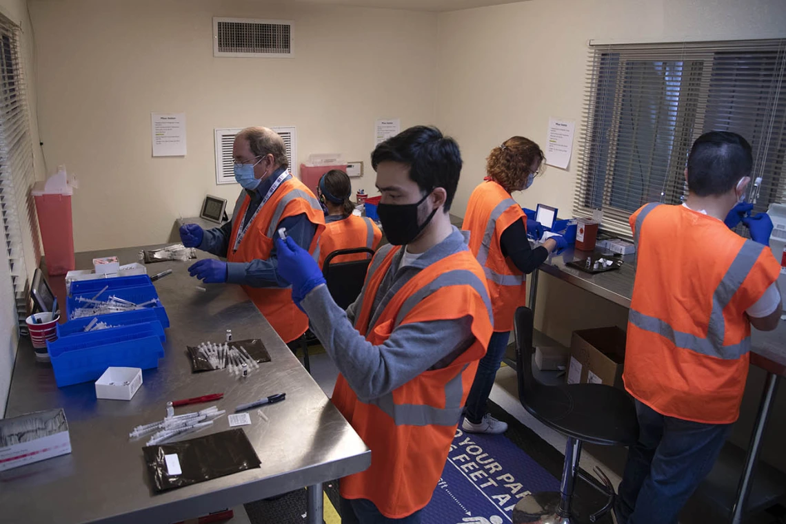 College of Pharmacy professor David Nix, PharmD (left) and 2017 alumnus Kenneth Olson, PharmD, prepare to mix the Pfizer vaccine with saline at the drive-through POD at the University of Arizona.