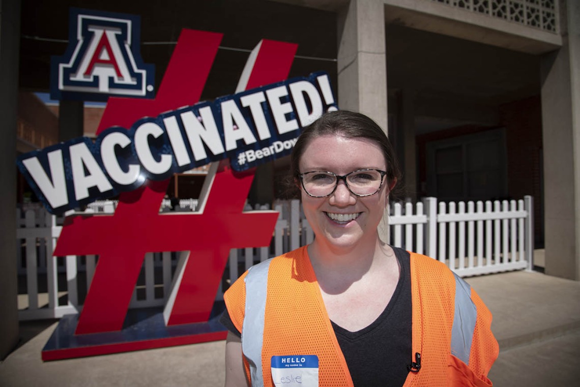Leslie Farland, ScD, assistant professor at the Mel and Enid Zuckerman College of Public Health, poses by a sign at the Pima County POD at the University of Arizona to encourage others to receive COVID-19 vaccinations.