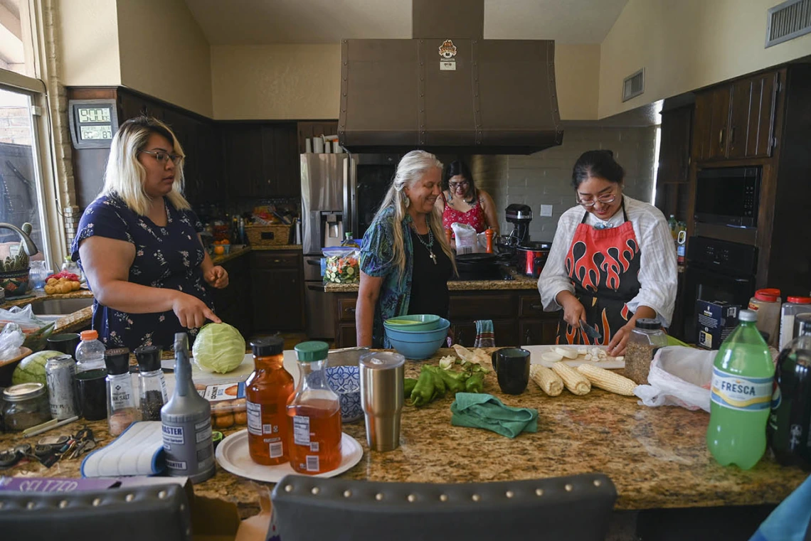 Diné College students Angel Leslie (left), Alyssa Joe (back) and program manager Kaitlyn Haskie (right) make fry bread and prepare mutton stew for a meal at the home of Kathleen Rodgers, PhD, who developed and leads the URBRAIN program.