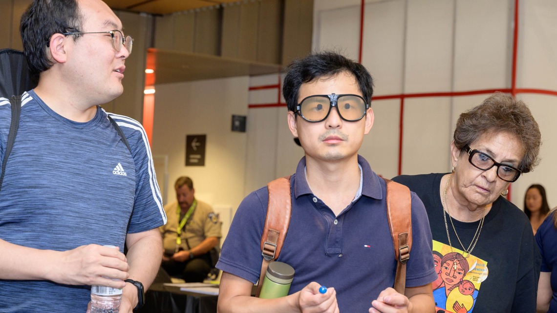 Attendees at the inaugural Feast for Your Brain event at the Health Sciences Innovation Building on Sept. 10 try on special eyeglasses that simulate macular degenerative disease. 