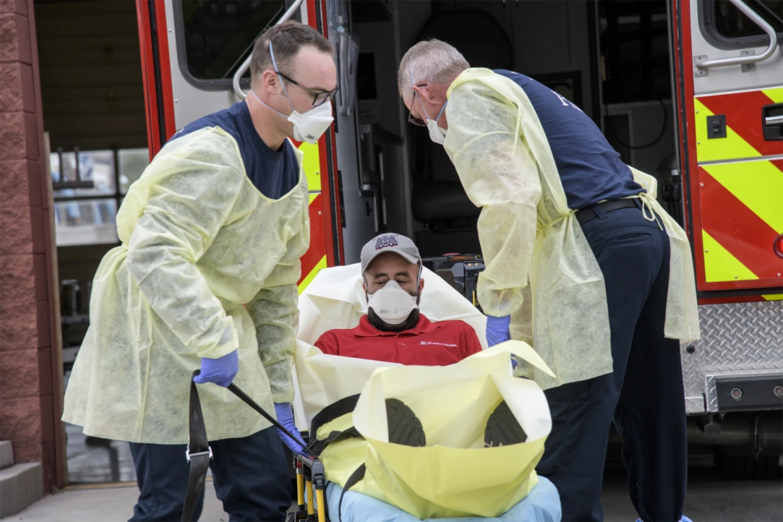 Firefighters Taylor Parrish and Chris LaFave wrap Jonathan Sexton, PhD, in a protective barrier to demonstrate how to prevent further spread of a virus during an ambulance trip to the hospital.