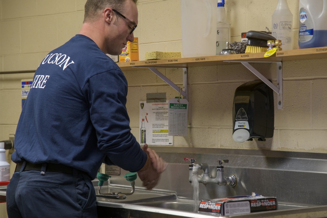 Tucson Fire Department’s Taylor Parrish washes his hands after sanitizing equipment as part of a training to help first responders prevent the spread of an infectious disease. 