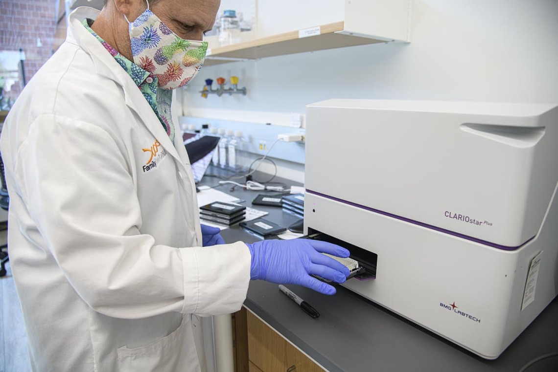 Matthew Kaplan, manager for University of Arizona Functional Genomics Core, places an antibody assay plate on a ClarioStar plate reader.