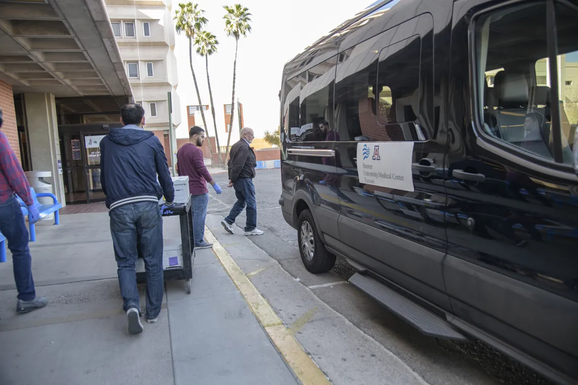 Lab Techs stand by before loading the kits into a Banner van as local media prepares to film.