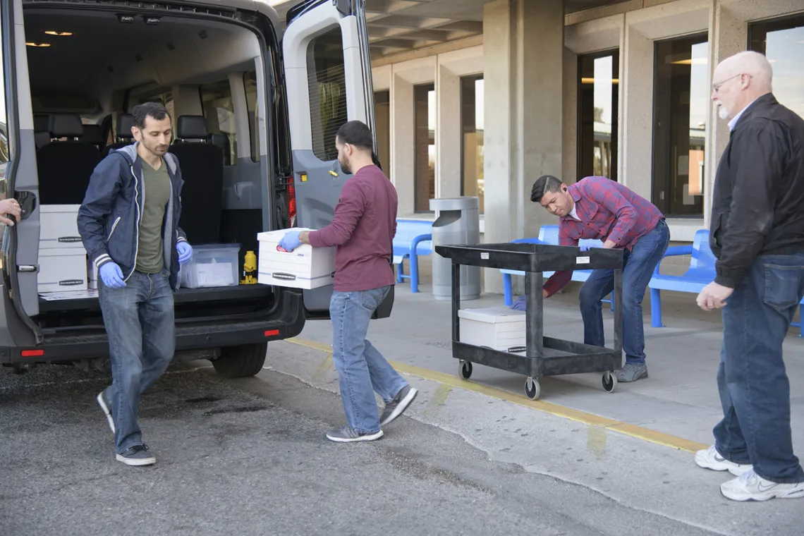 Lab Techs stand by before loading the kits into a Banner van as local media prepares to film.