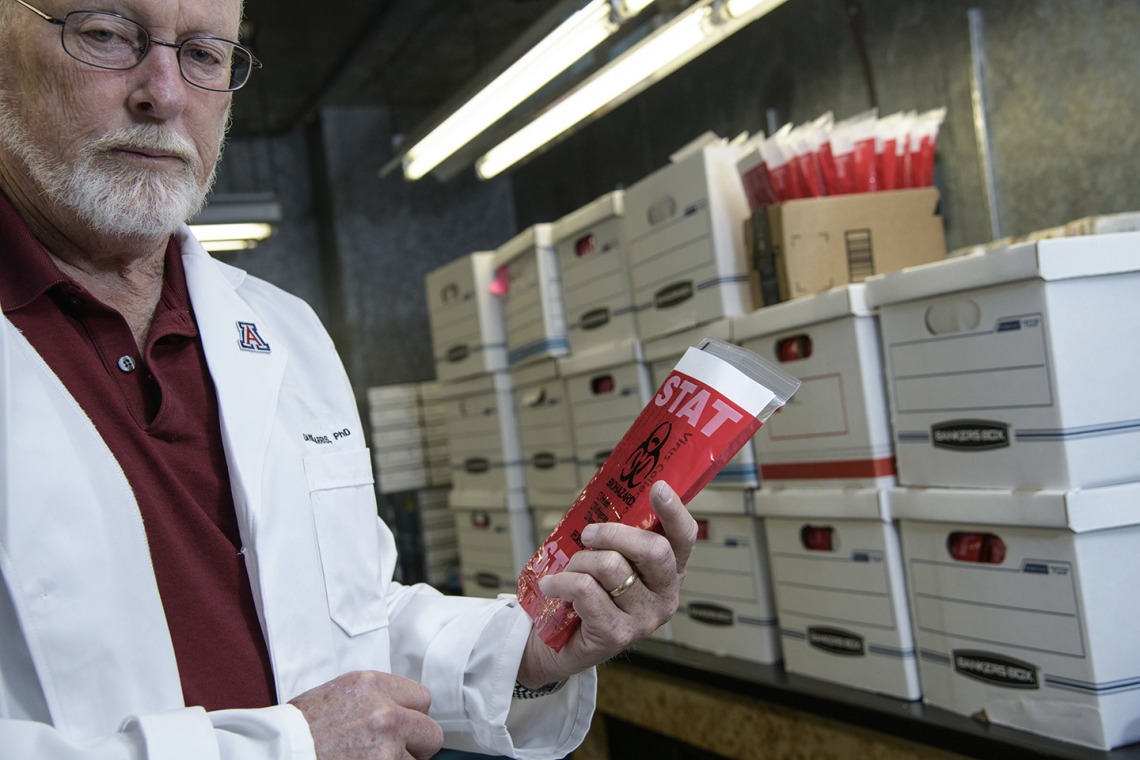David T. Harris, PhD, executive director of University of Arizona Health Sciences Biorepository, holds a COVID-19 sample collection kit inside the freezer.